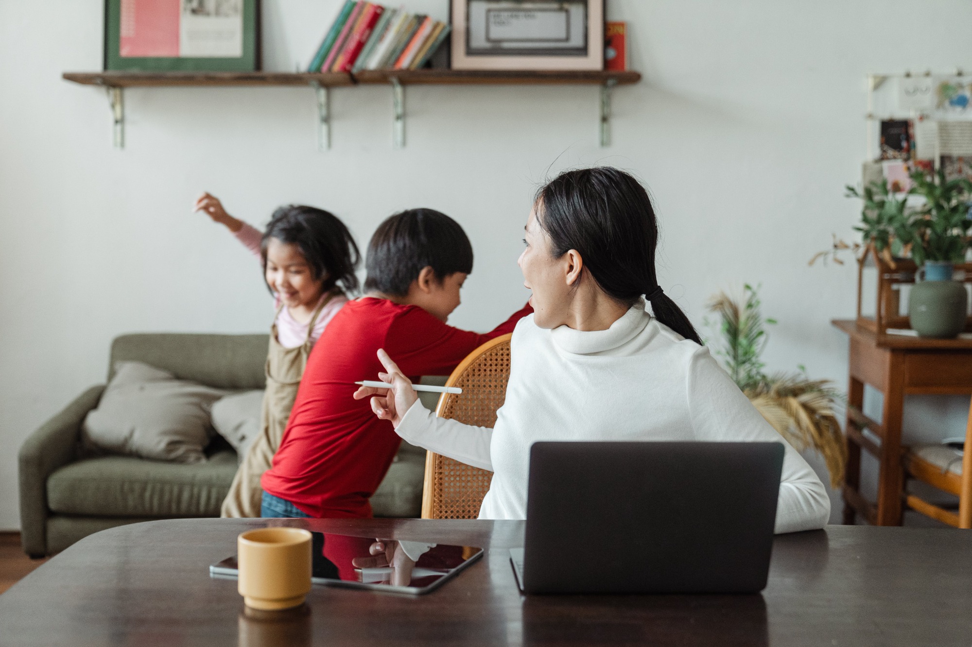 A bustling family living room with parents and children engaged in various activities, showcasing the challenges of maintaining a clean home amidst a busy lifestyle.