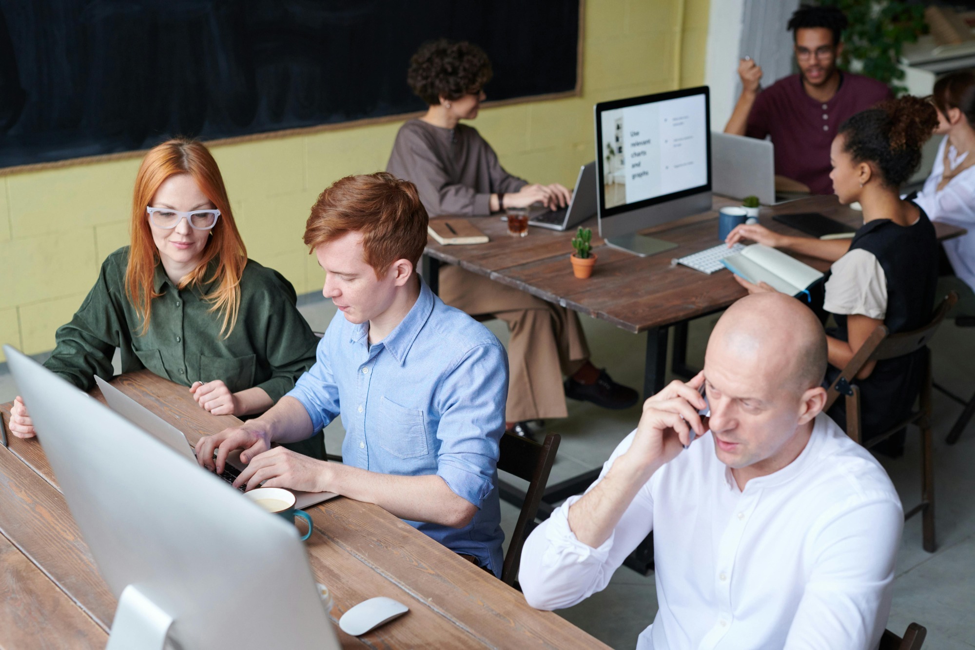 A photo of a busy professionals typing on a laptop while multitasking on a phone call.