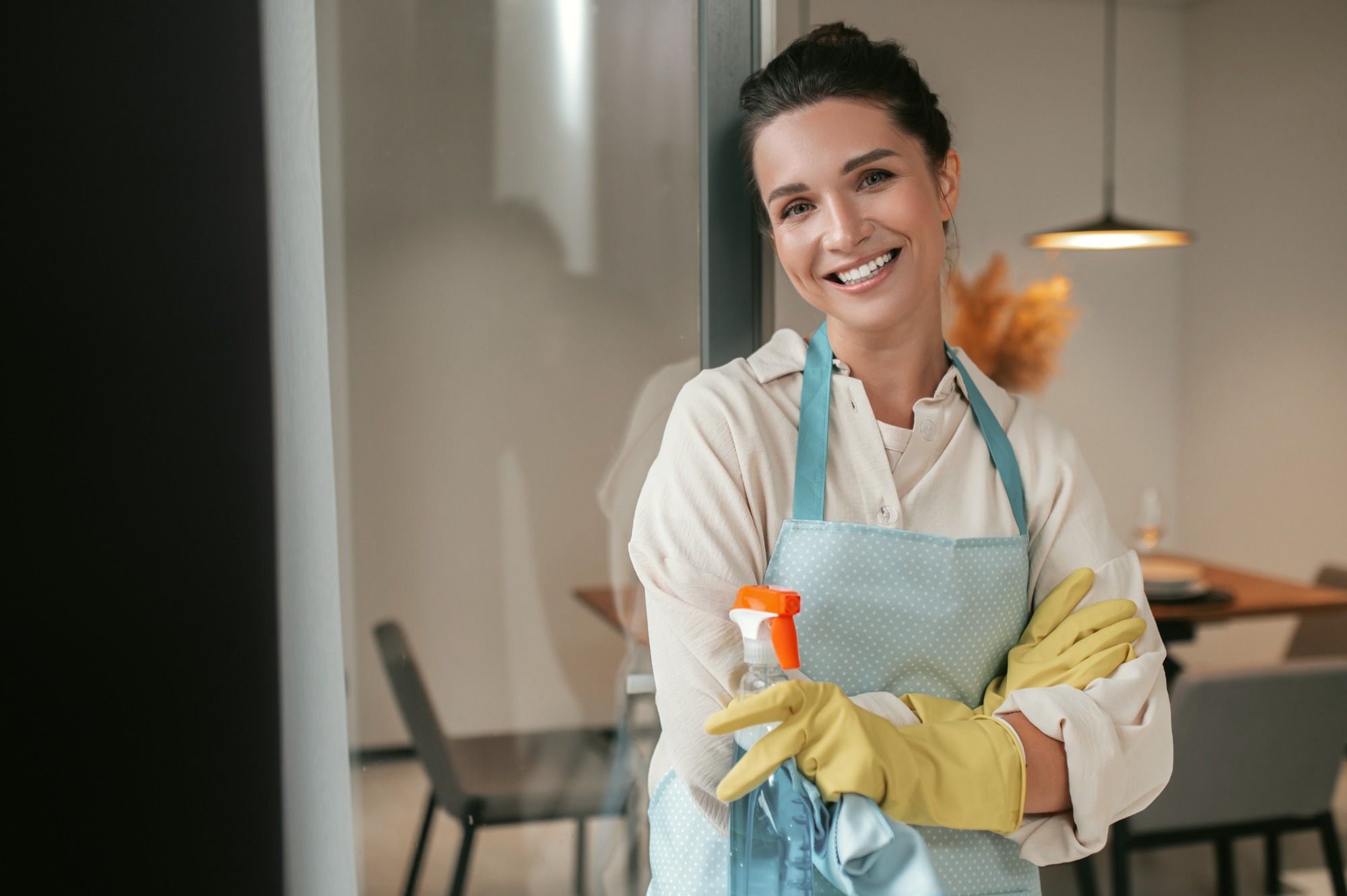 A smiling professional cleaner in Providence holding a spray bottle, ready to tackle house cleaning tasks