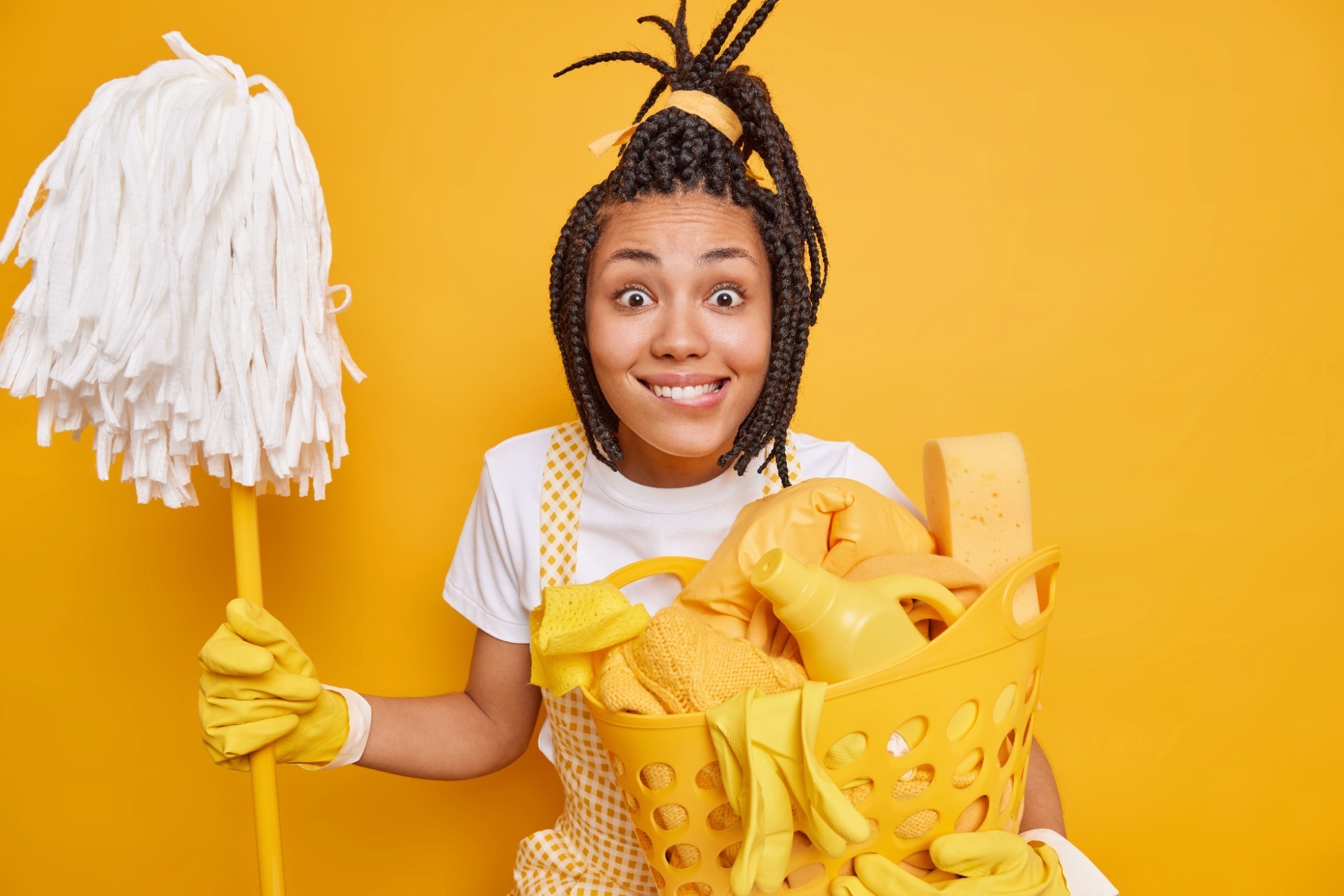 A smiling woman holding a mop and bucket, ready for cleaning.