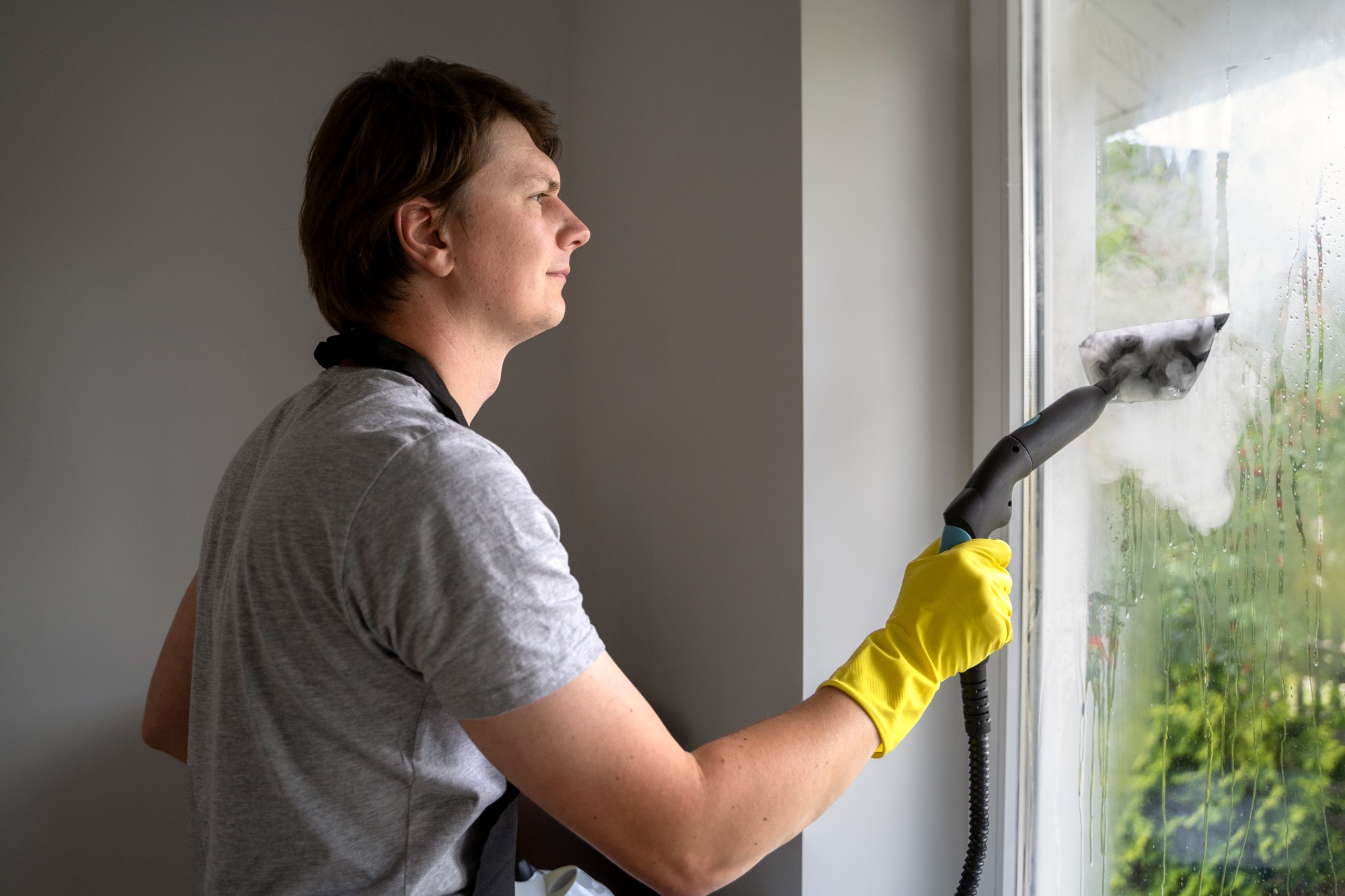 Window cleaning requires skill and precision to ensure a streak-free finish. The man in the photo is diligently cleaning a large glass window, using a squeegee and a microfiber cloth to remove dirt and grime. His careful technique shows the importance of attention to detail in achieving spotless windows.