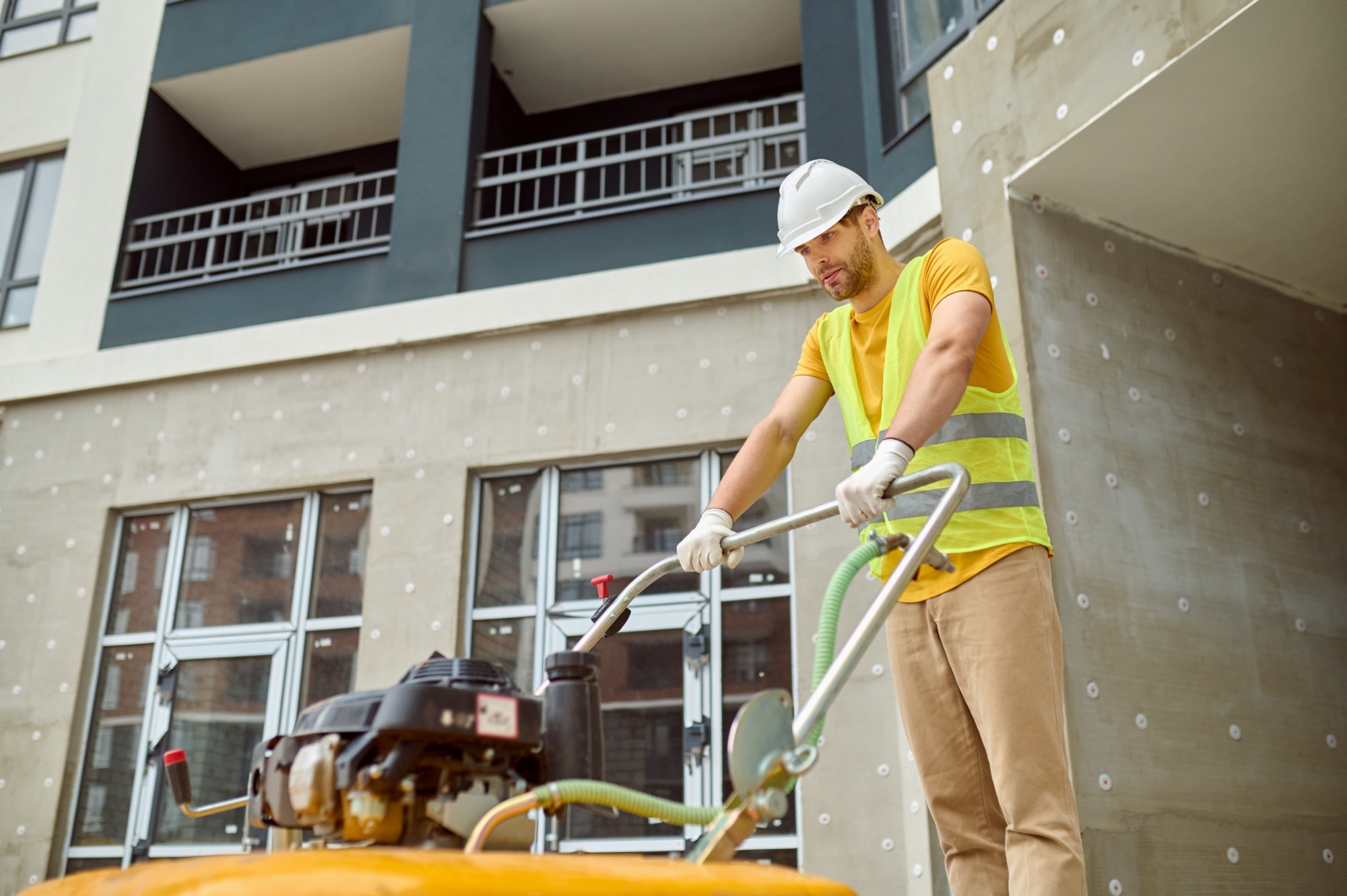 A cleaning professional wiping dust off a large window in a newly constructed, modern home with gleaming floors and countertops